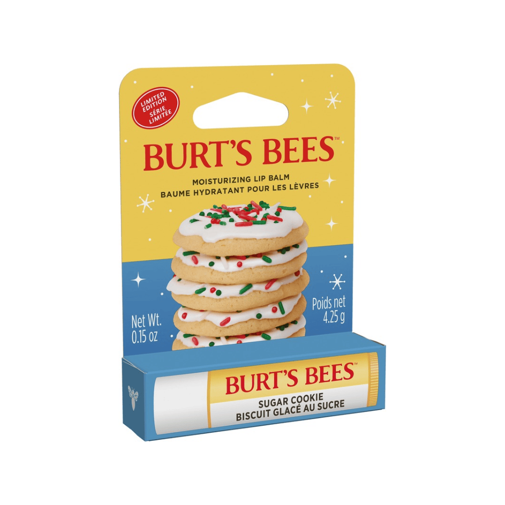 Burt's Bees Sugar Cookie moisturizing lip balm in its retail packaging, featuring a yellow and blue card with an illustration of decorated sugar cookies and a matching blue and yellow tube.