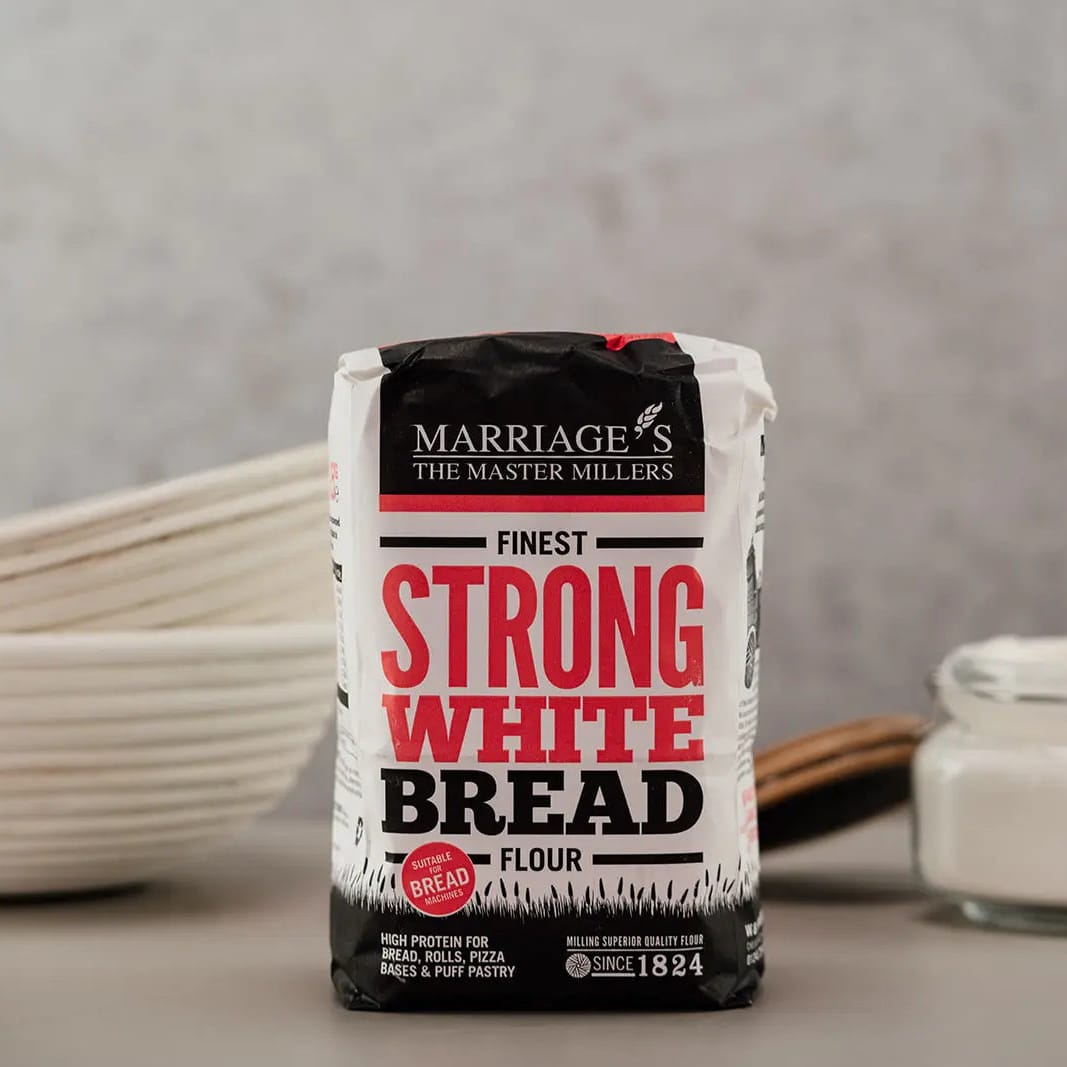 Bag of Marriage The Master Millers Strong White Bread Flour on a gray background with bowls and flour in the background.