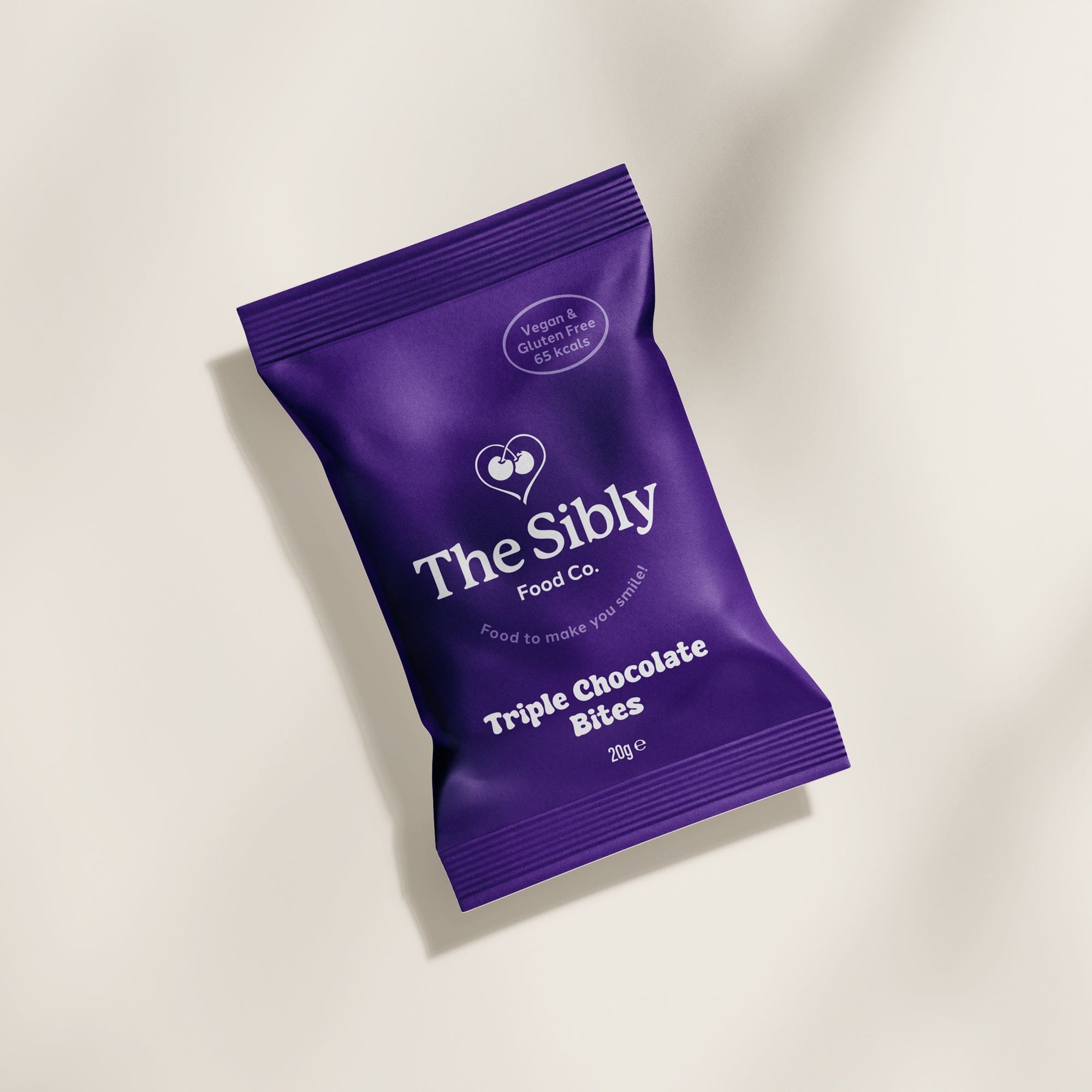 Purple package of The Sibly Food Co. Triple Chocolate Bites on a beige background