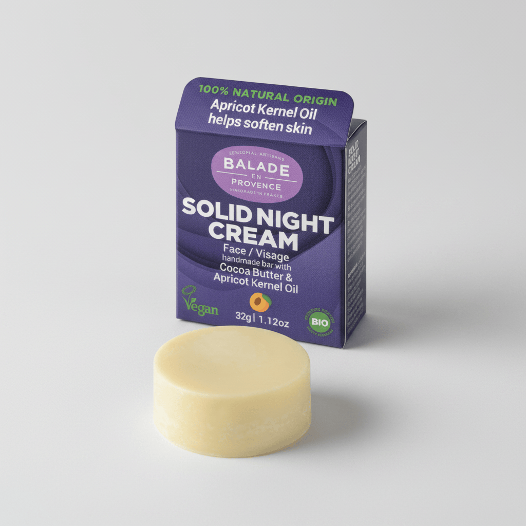 A round beige solid night cream bar in front of its purple and white Balade Provence packaging box on a white background.