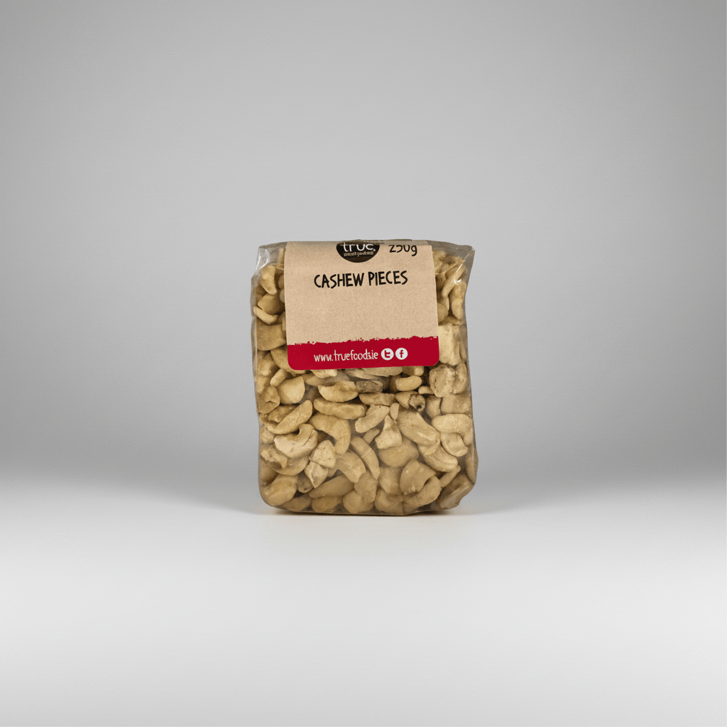 A clear plastic bag of True Food Cashew Pieces, showing the light beige cashews inside, with a kraft paper label and red stripe on a white background.