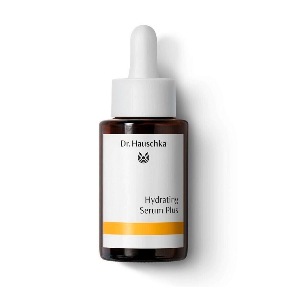 A bottle of Dr. Hauschka Hydrating Serum Plus with a white dropper cap and a white label featuring a yellow-orange accent stripe, set against a plain white background.