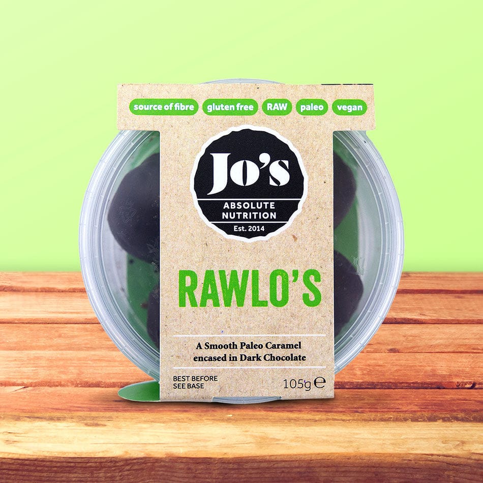 Jo's Absolute Nutrition Rawlo's paleo caramel chocolate encased in a clear plastic tub with a kraft paper label, set on a wooden surface against a light green background.