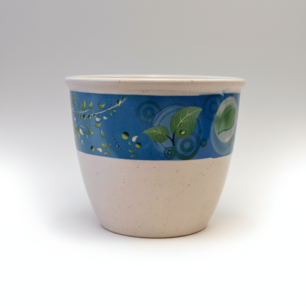A handmade ceramic planter pot with a speckled beige lower body and a blue band decorated with green leaves and botanical patterns, shown against a plain white background.
