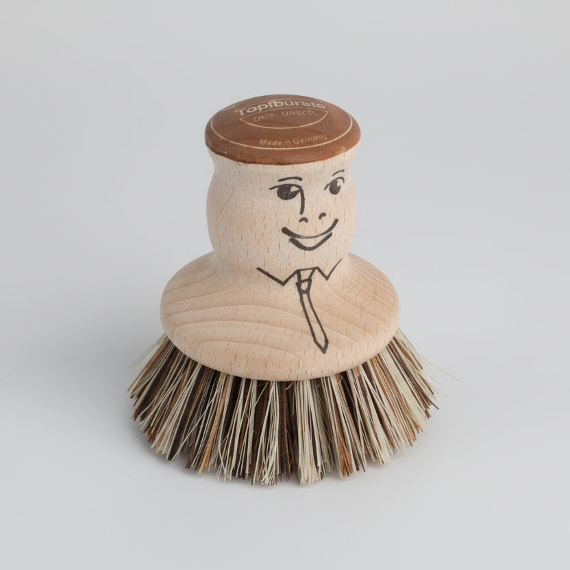 Wooden dish brush with a face design on a white background